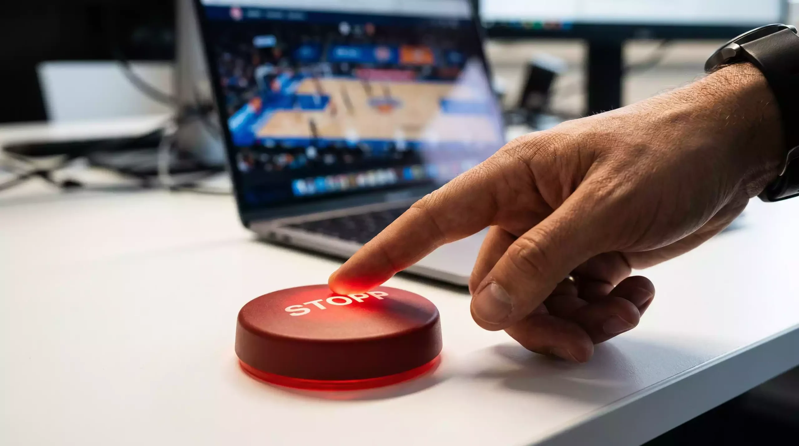 Spielerschutz bei Sportwetten – Hand drückt Stopp-Taste an einem Laptop